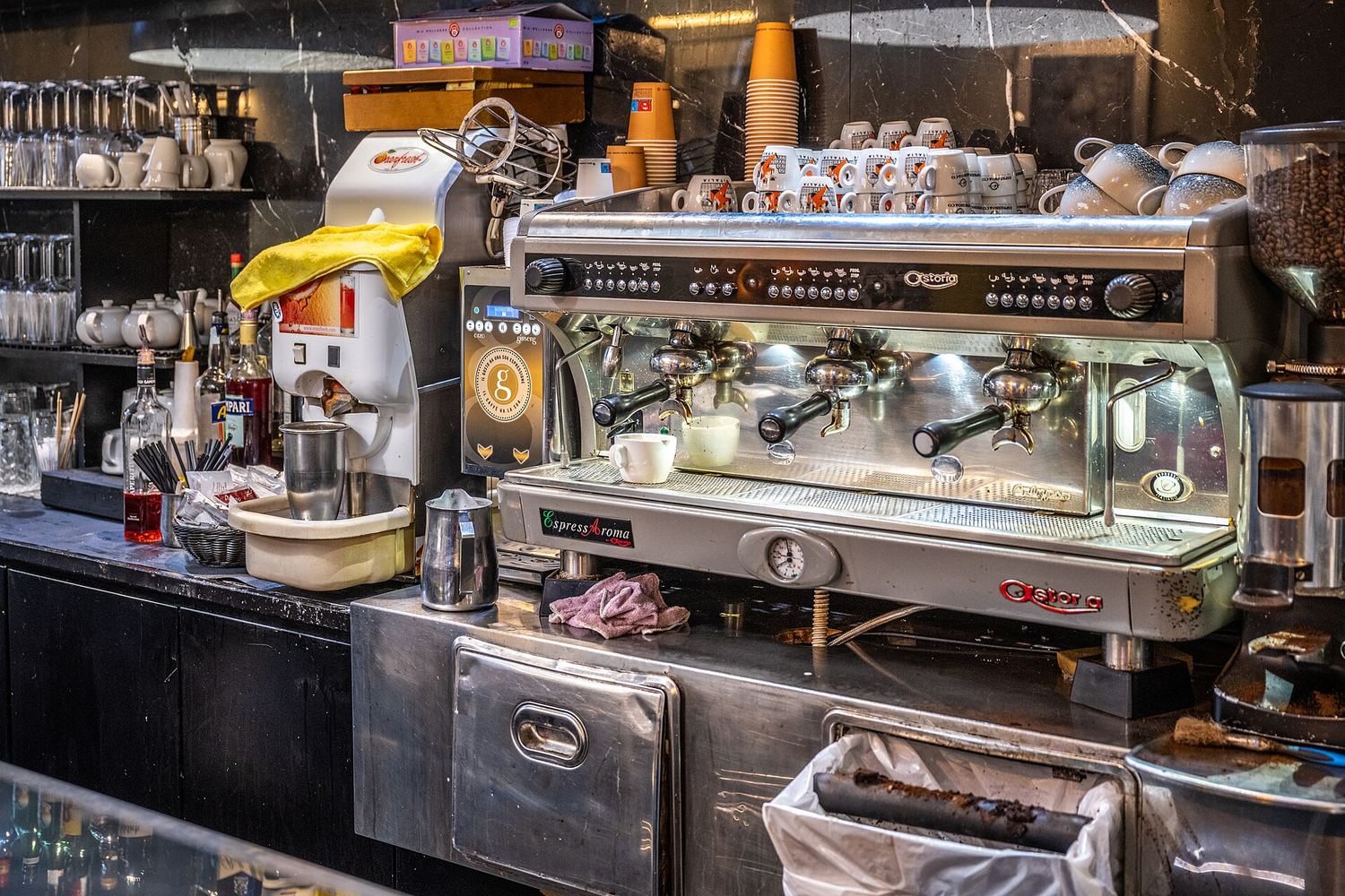 Bancone di un bar italiano con la macchina dell'espresso, le tazzine impilate e il macinino