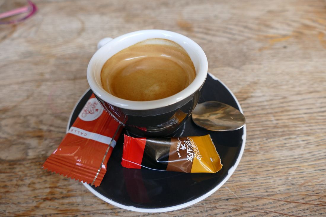 Una tazzina di caffè espresso con due bustine di zucchero su un tavolo di legno
